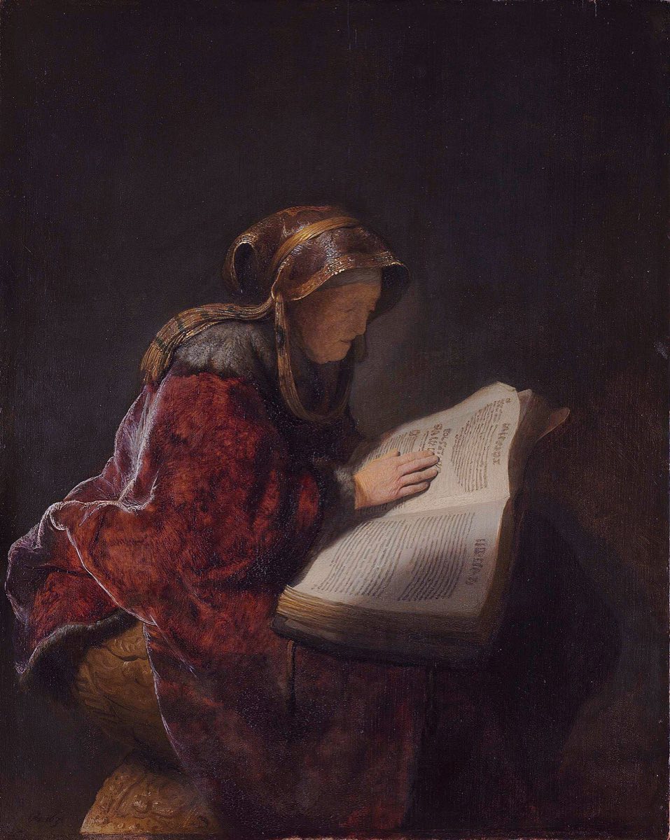 Rembrandt's painting of an aged woman in a rich red robe and headdress, bent close over a great Hebrew book, one hand resting on the page.
