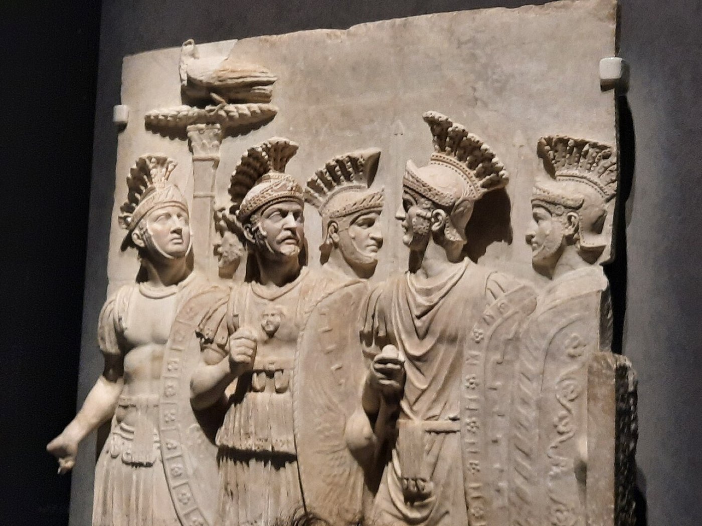 A marble relief of Roman Praetorian soldiers in armor with shields and an eagle standard, standing in close formation.