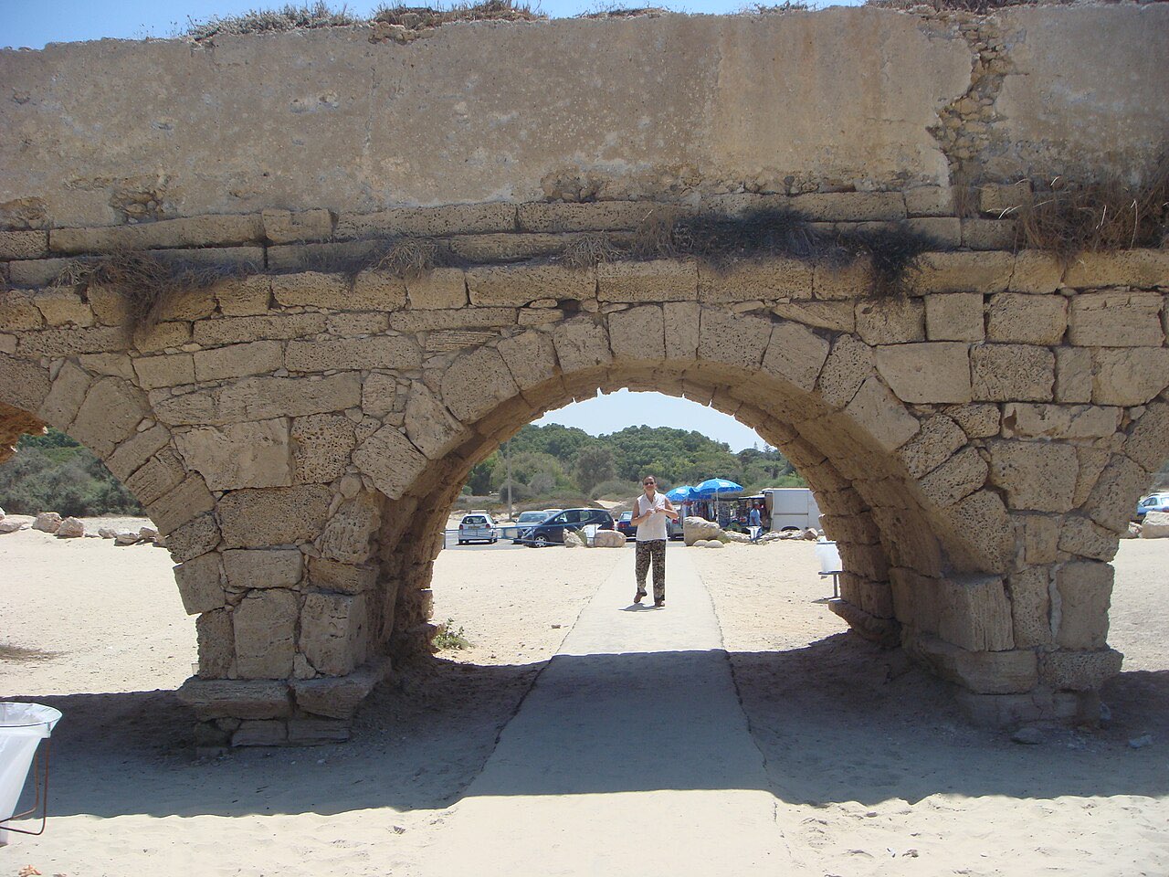 Arches of the Roman aqueduct at Caesarea Maritima running along the sandy Mediterranean beach.