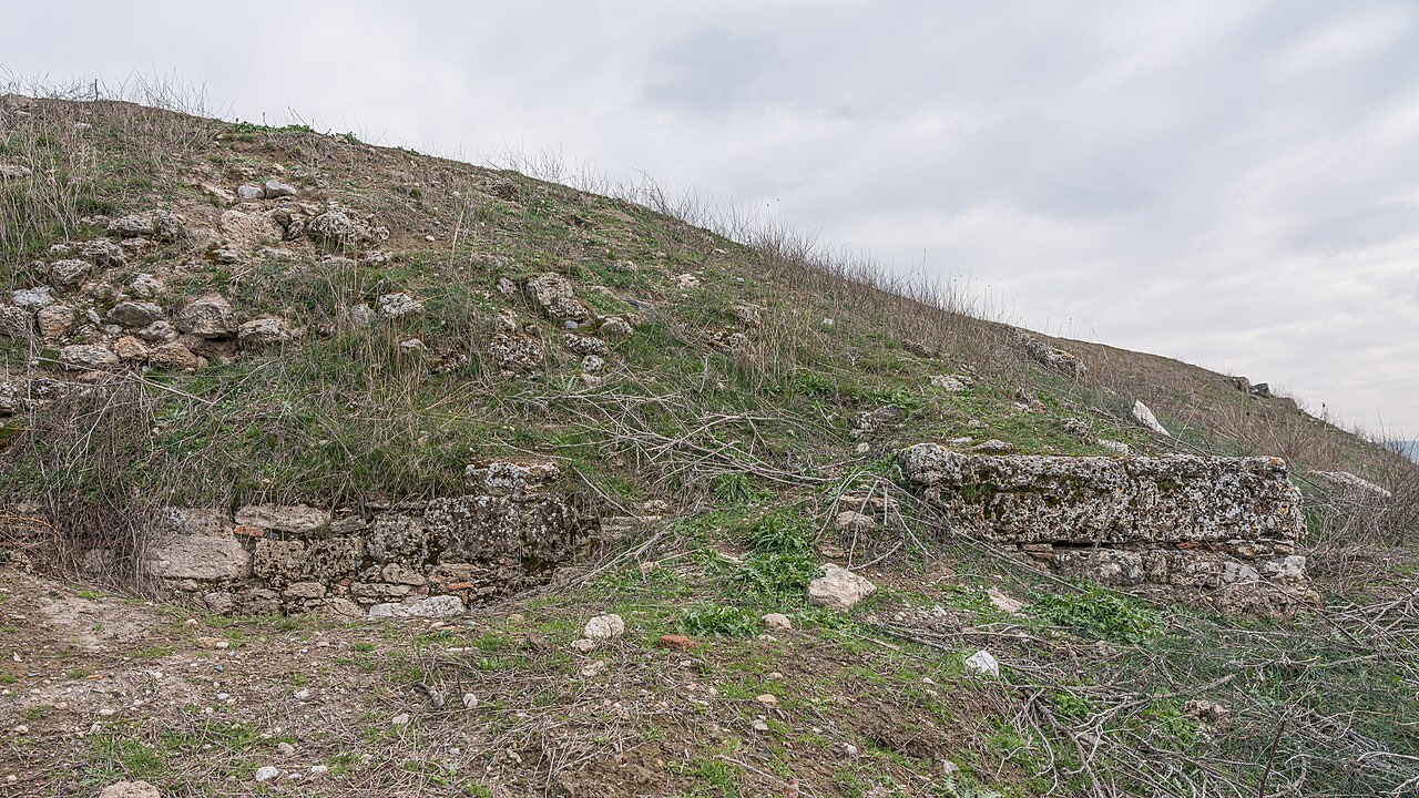 The grassy, unexcavated mound of Colossae under a gray sky -- the buried city of the church Epaphras planted.