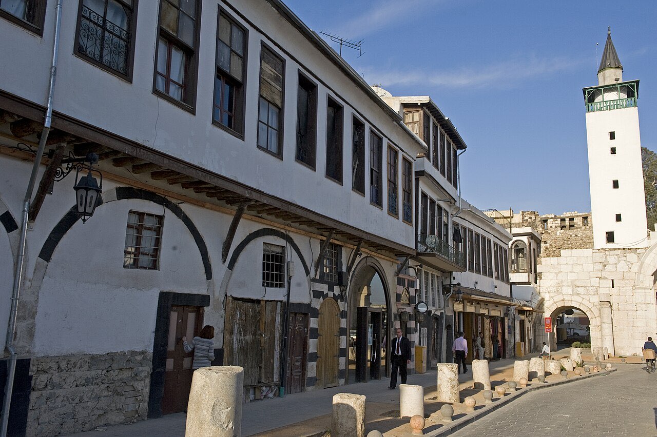 The Street Called Straight in Damascus: a long paved street running toward the Roman East Gate, flanked by shops and a minaret.
