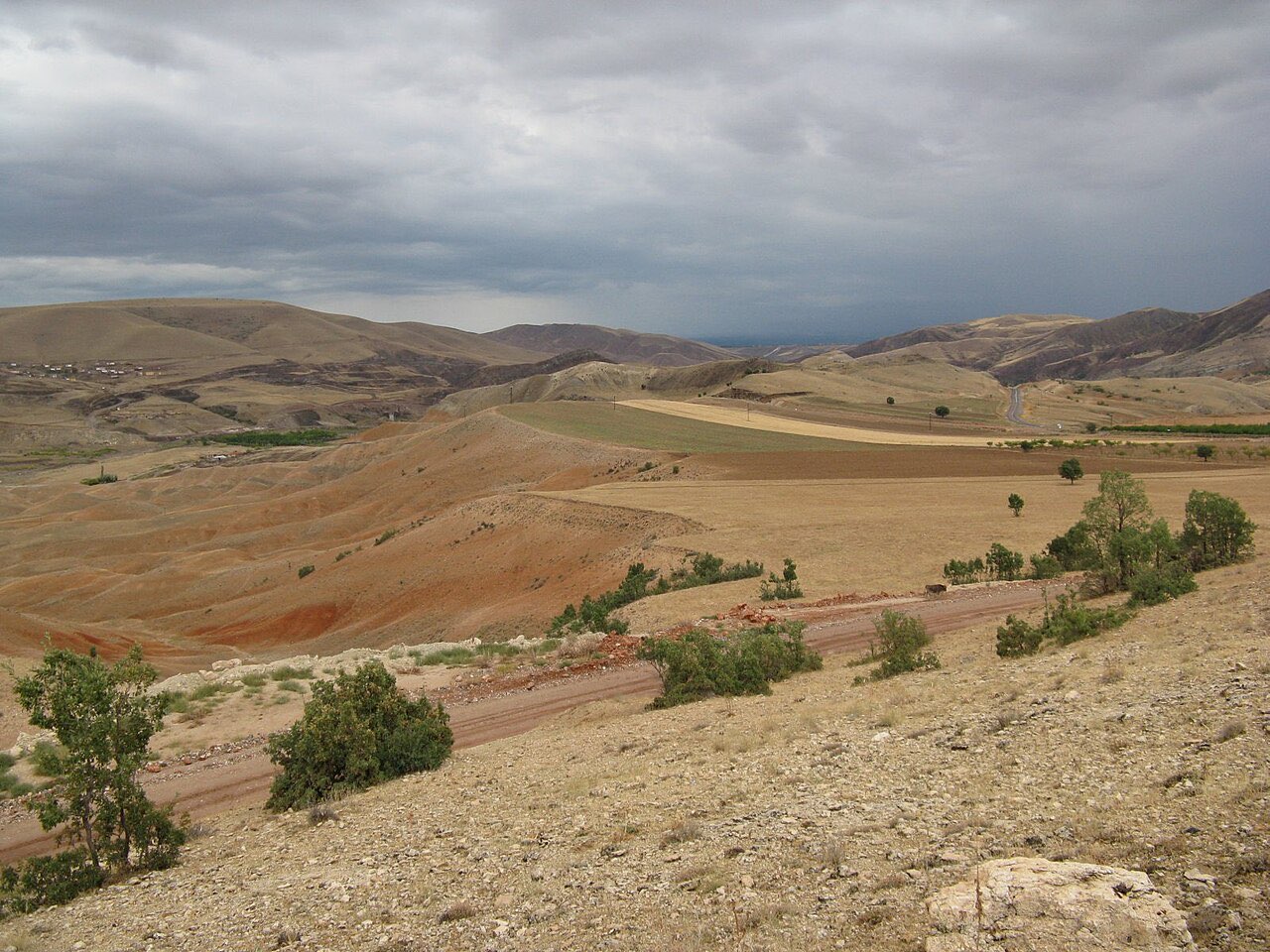 The open Anatolian plateau: dry rolling steppe, patches of cultivated field, and bare hills under a wide sky.