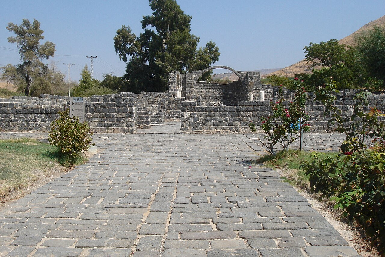 Ruins of the Byzantine monastery at Kursi: black basalt walls and a stone arch under a bright sky.