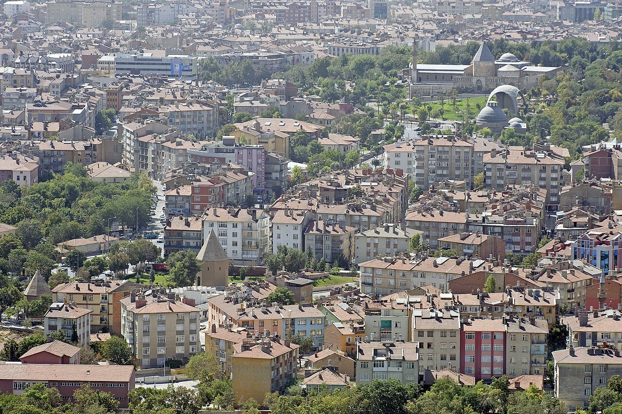 View over the rooftops of modern Konya toward the tree-covered Alaeddin hill at the city's center.