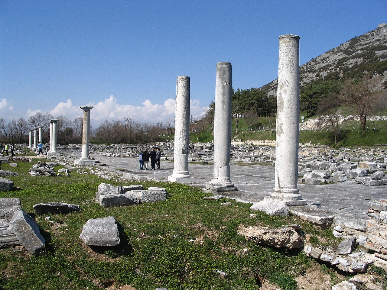White marble columns of the agora at Philippi in Macedonia, with the town's acropolis hill rising behind.