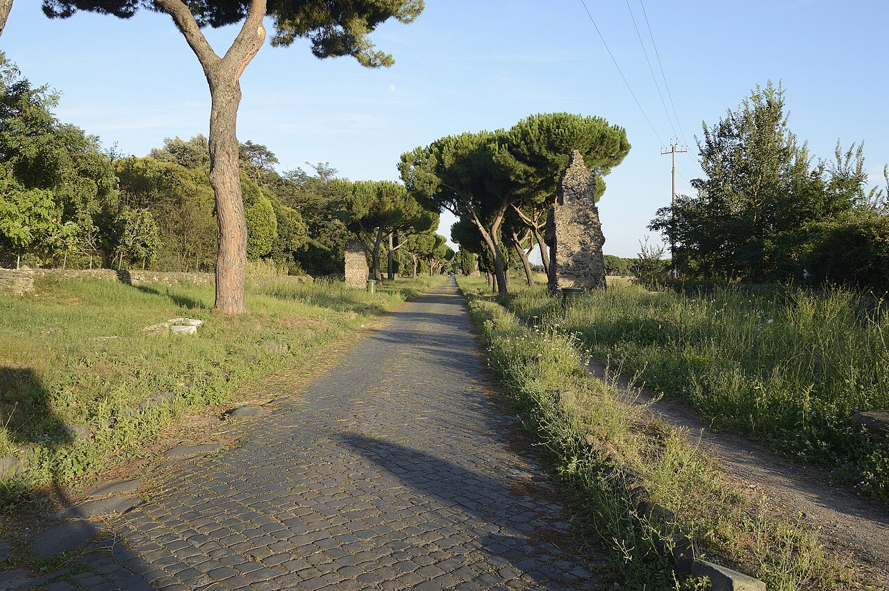 The Appian Way stretching into the distance between pines -- the road out of Rome that Demas took toward Thessalonica.
