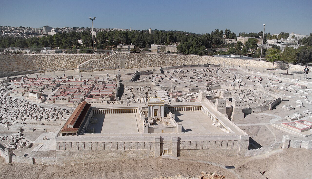 Scale model of Herod's Temple: a white stone sanctuary with gold trim standing in a broad colonnaded court, surrounded by the packed rooftops of first-century Jerusalem.